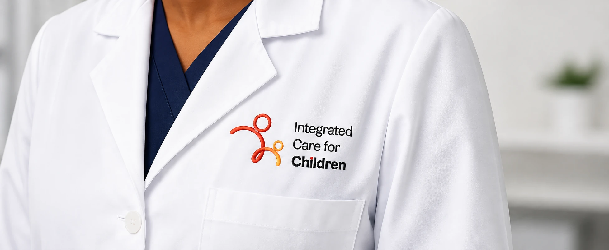 A doctor's white coat with the Integrated Care for Children logo embroidered on the chest.
