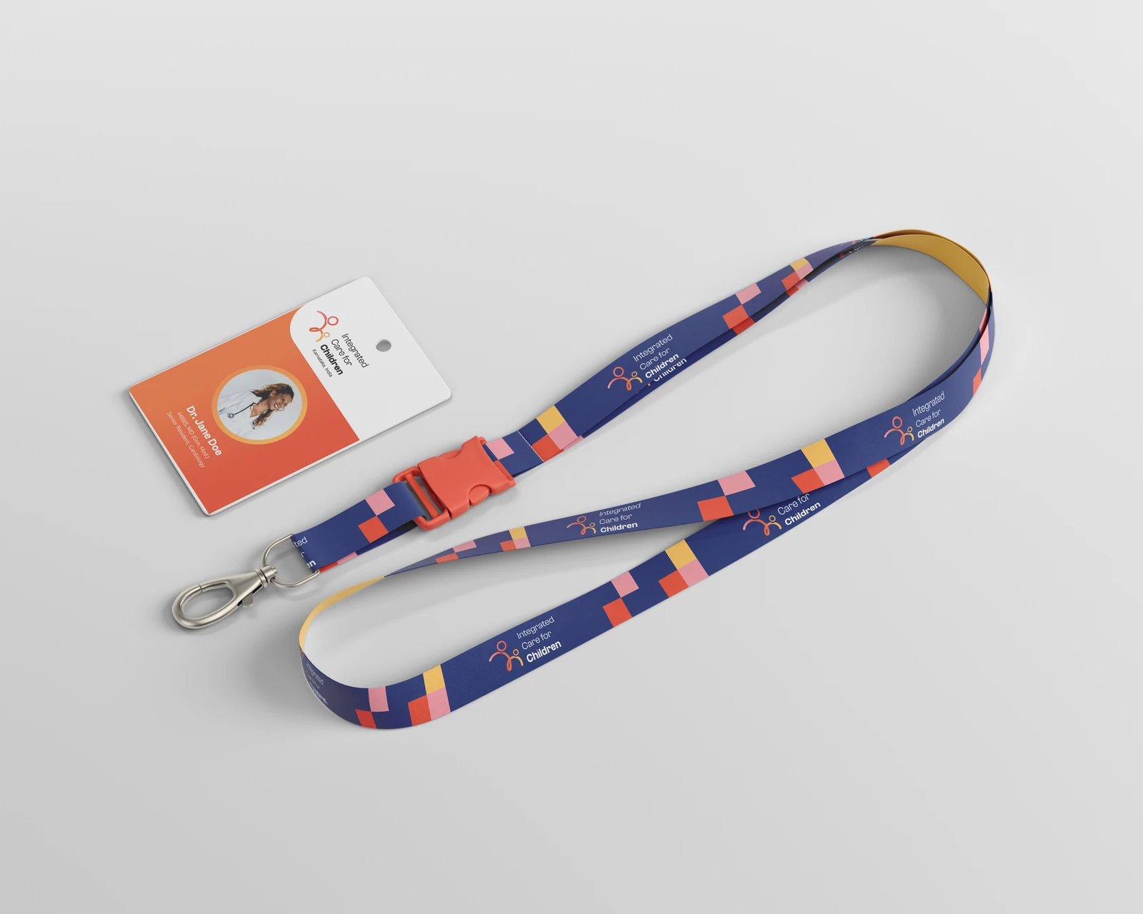 A staff ID badge on a branded lanyard: the logo and the wearer's photograph on the card, with the lanyard carrying the logo and a run of the identity's colour blocks.