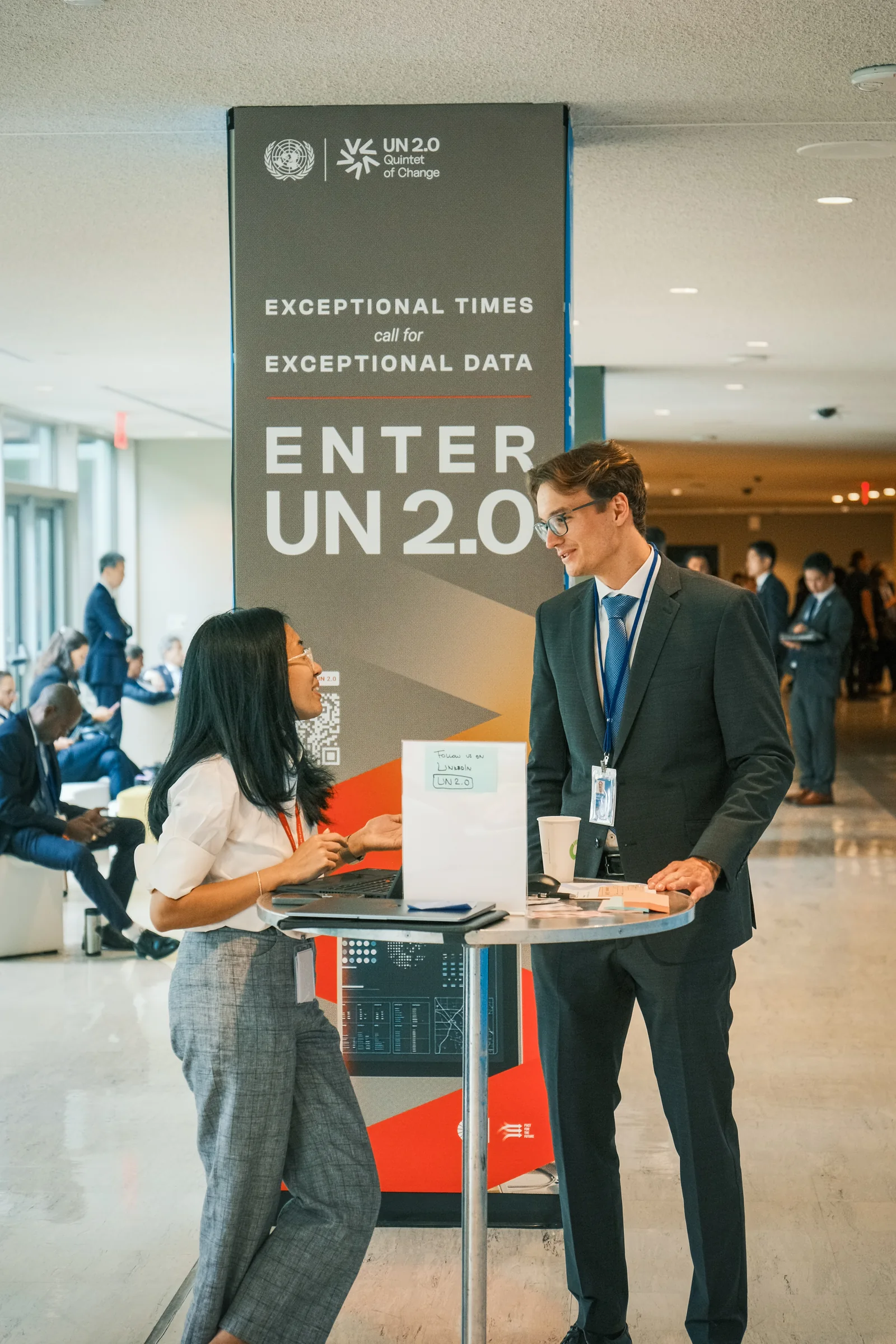 Two visitors talking across a high table beside the Exceptional Data column