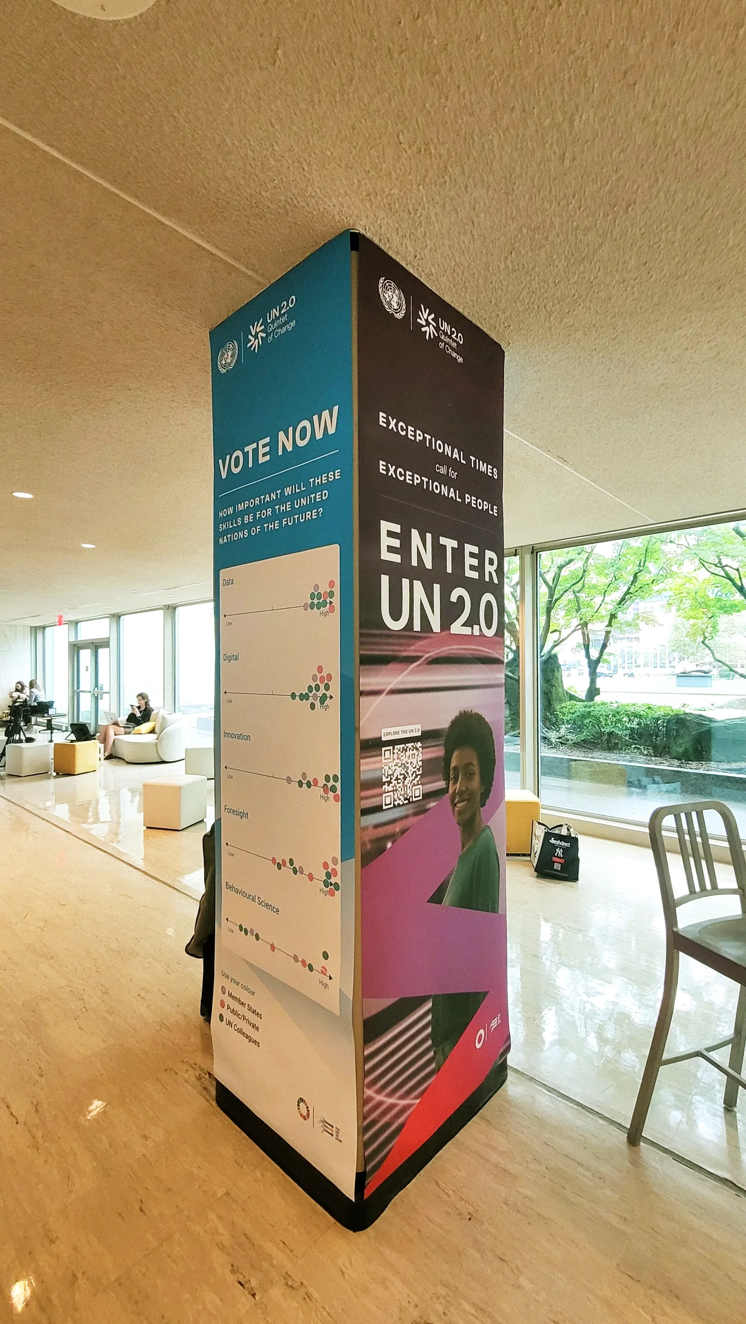 A column in the lounge with an Enter UN 2.0 banner on one face and a Vote Now banner on the next, dots already placed against the answers