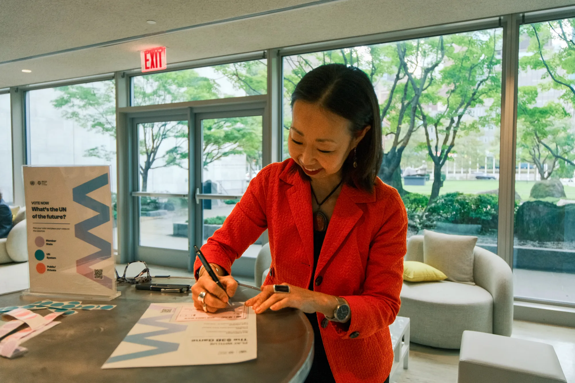 A visitor filling in a voting card at the table, beside a card reading Vote now: what's the UN of the future?
